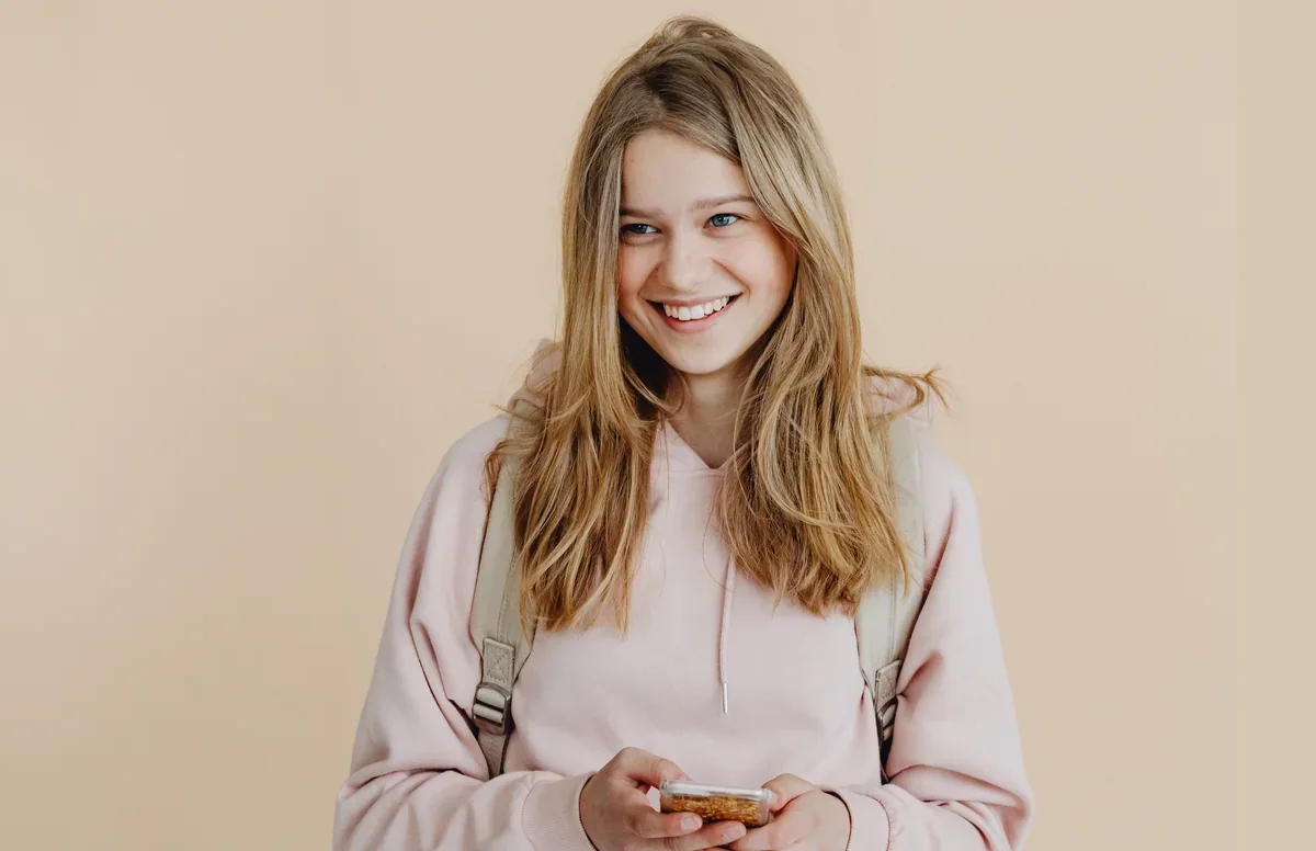 Smiling teenager holding a phone as a clean money gift reveal overlay appears on screen.